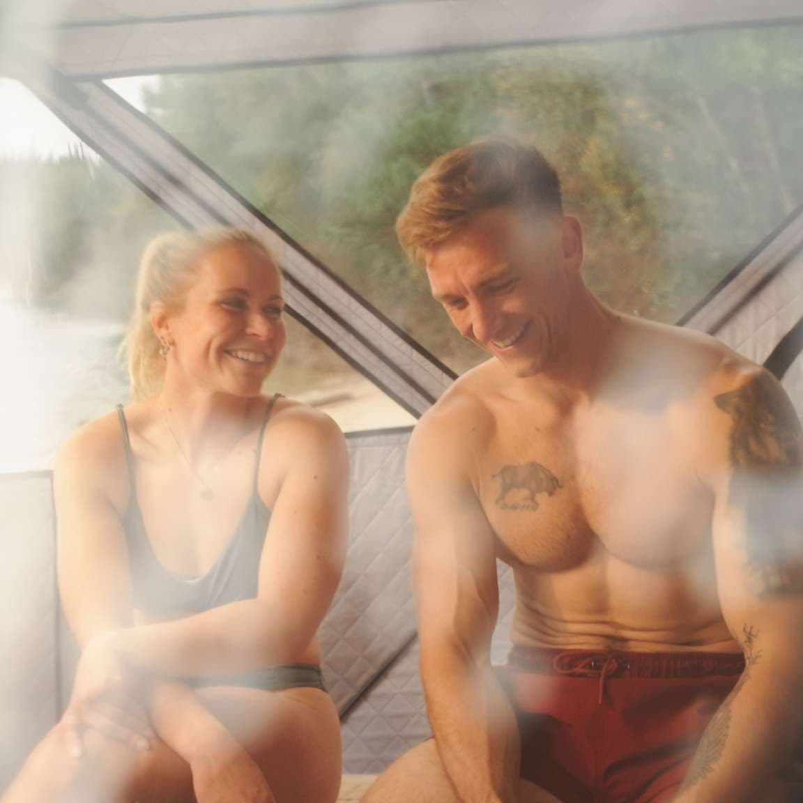 Twee mensen genieten van de warmte in de saunatent